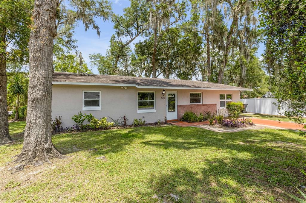 A single-story house with a light-colored exterior, brick accents, and a front lawn with trees — 380 JULIA AVENUE, ORANGE CITY, FL