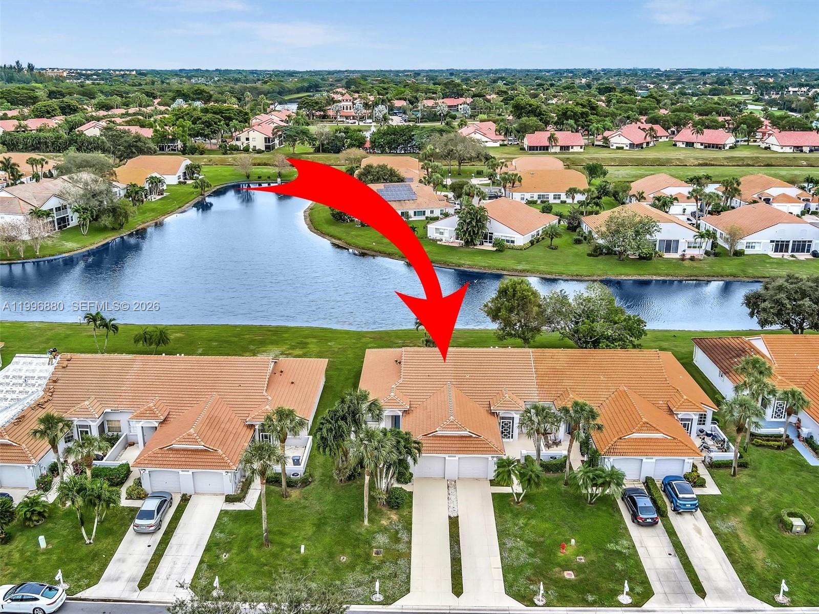 An aerial view shows a row of attached houses with orange tile roofs near a lake — 15212 W Tranquility Lake Dr # 15212, Delray Beach FL 33446, DELRAY BEACH, FL