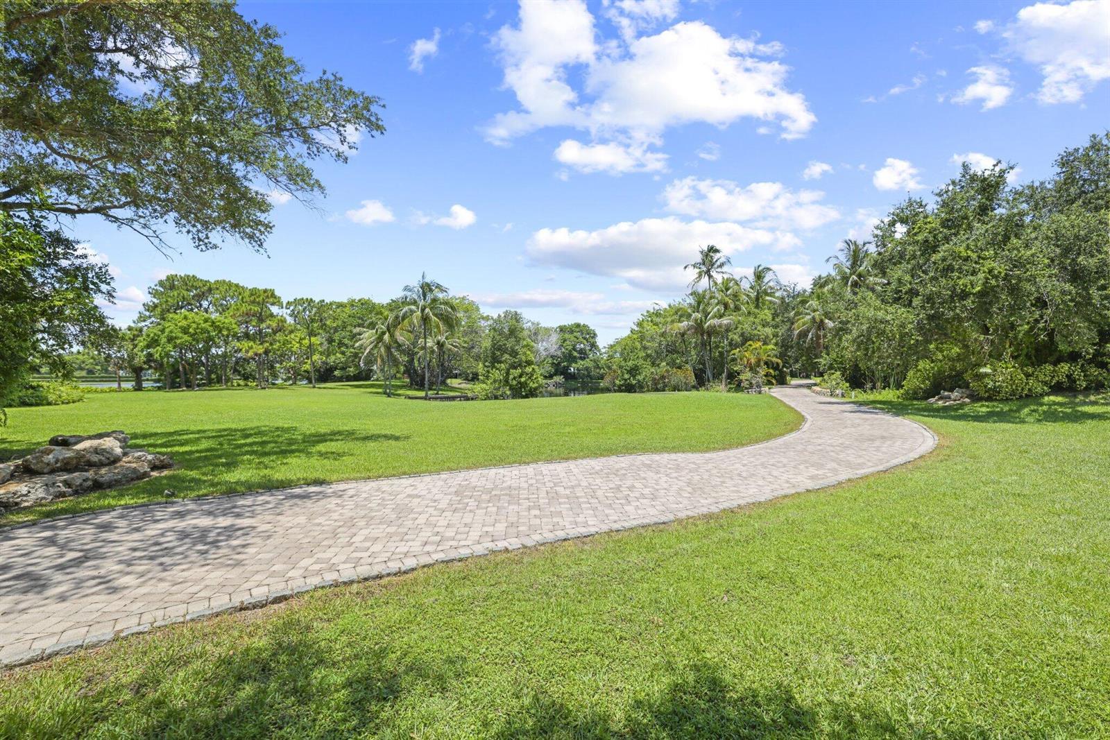 A paved driveway curves through a large green lawn surrounded by trees and palms — 6001 Le Lac Road, Boca Raton FL 33496, BOCA RATON, FL