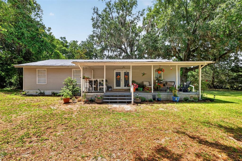 A single-story house with light-colored siding and a covered front porch sits on a lawn — 3848 WARM SPRINGS AVENUE, WILDWOOD, FL