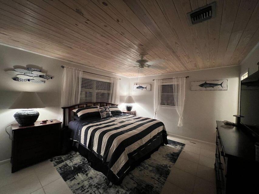 A bedroom features a wood-plank ceiling, a striped bedspread, and nautical wall art — 1540 Lantana Lane, FL 33043, FL