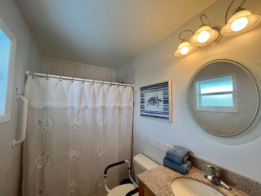 A bathroom features a shower with a white curtain, a round mirror, and a vanity — 1540 Lantana Lane, FL 33043, FL