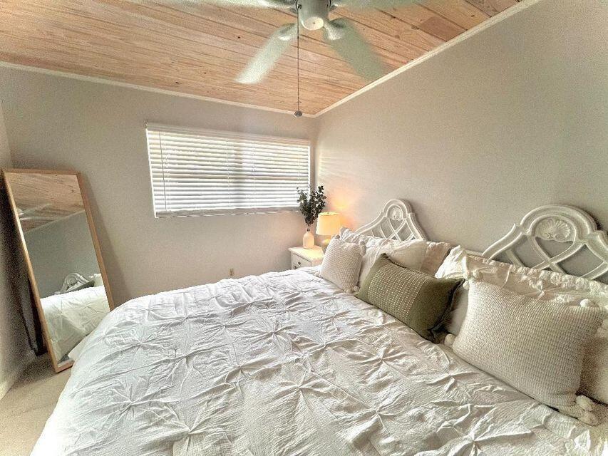 A bedroom features a white bed, a wood-paneled ceiling, and a full-length floor mirror — 1540 Lantana Lane, FL 33043, FL