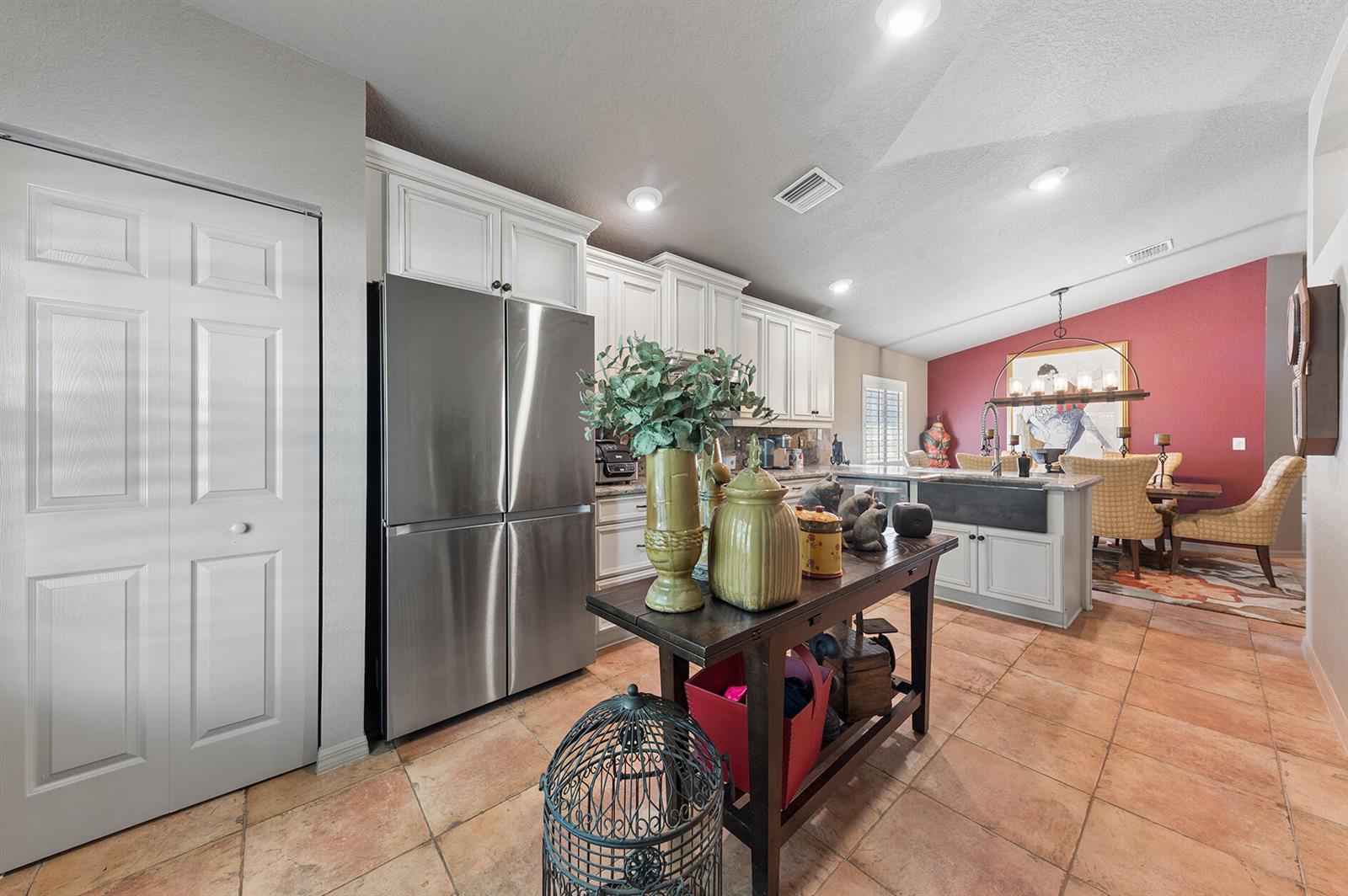 A kitchen features white cabinetry, stainless steel appliances, a center island, and terracotta tile flooring — 5318 Vernio Lane, Boynton Beach FL 33437, BOYNTON BEACH, FL