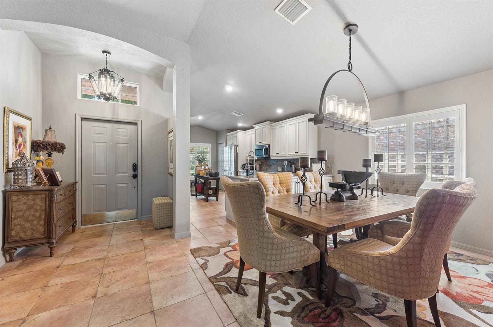 A dining area with a wooden table and chairs sits adjacent to an entryway and kitchen — 5318 Vernio Lane, Boynton Beach FL 33437, BOYNTON BEACH, FL