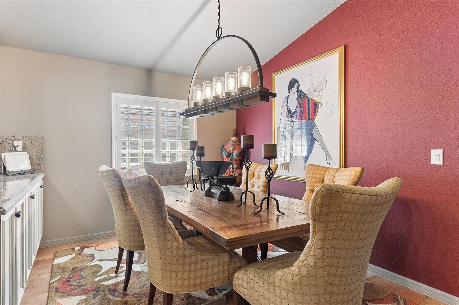 A dining room features a wooden table, upholstered chairs, a chandelier, and a red wall — 5318 Vernio Lane, Boynton Beach FL 33437, BOYNTON BEACH, FL