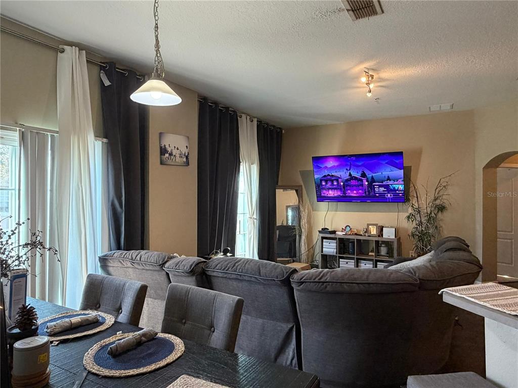 A living room with a large gray sectional sofa, a wall-mounted television, and dining area — 6488 S GOLDEN ROD UNIT 43A, ORLANDO, FL