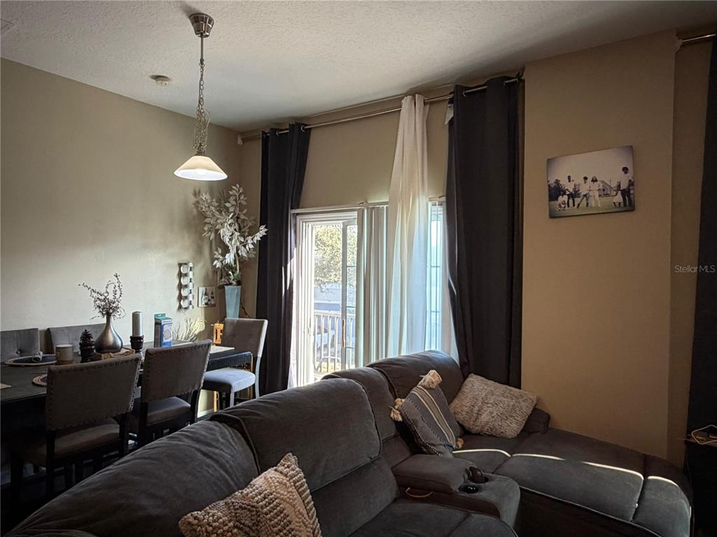 A living room with a gray sectional sofa, dining area, and sliding glass balcony doors — 6488 S GOLDEN ROD UNIT 43A, ORLANDO, FL