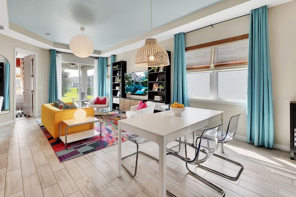 A bright living and dining area features a yellow sofa, colorful rug, and transparent chairs — 255 NORTHCOTE COURT, DELAND, FL