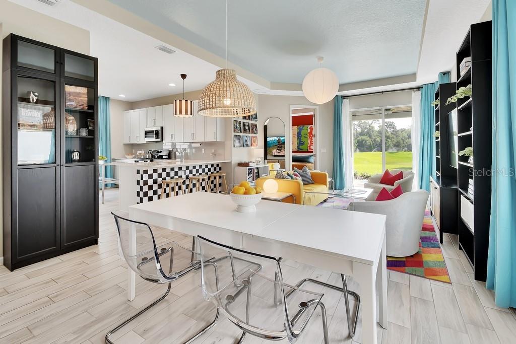 An open-concept living and dining area features a checkered kitchen island and light wood flooring — 255 NORTHCOTE COURT, DELAND, FL