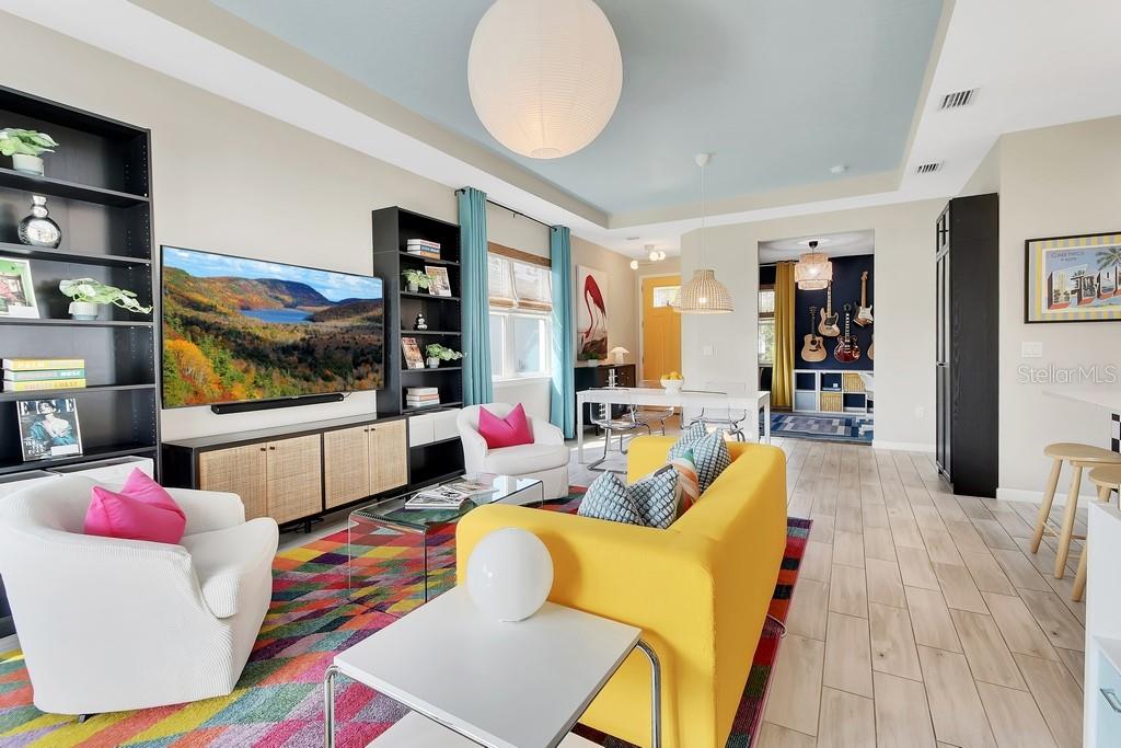 A living room features a yellow sofa, white armchairs, a colorful rug, and built-in shelving — 255 NORTHCOTE COURT, DELAND, FL