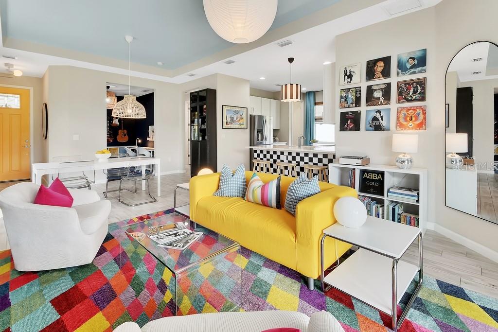 A colorful living room features a yellow sofa, a vibrant geometric rug, and vinyl record decor — 255 NORTHCOTE COURT, DELAND, FL