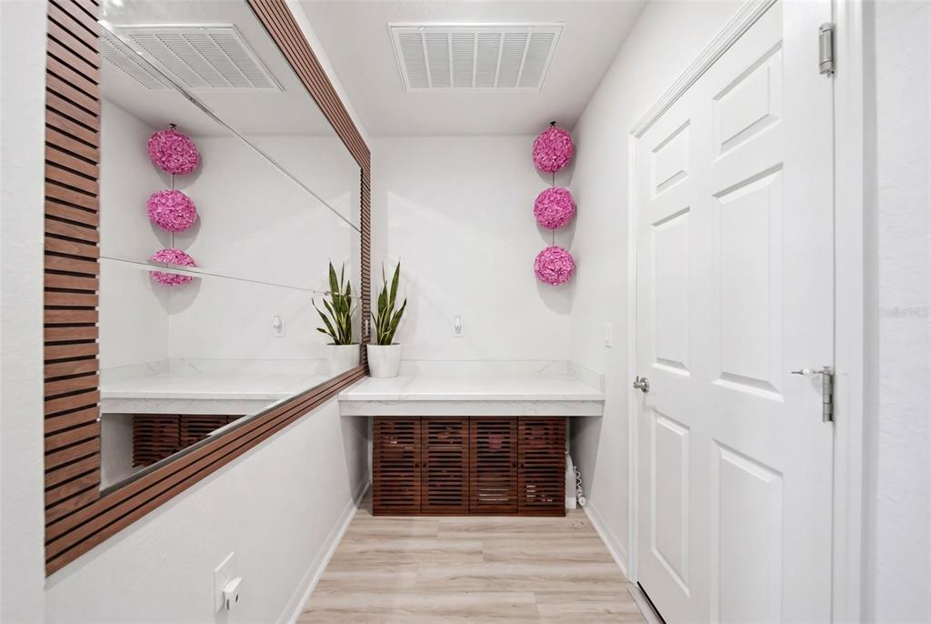 A small hallway features a marble-topped console, slatted wood cabinets, a large mirror, and decor — 1862 DAYSTAR DRIVE, HAINES CITY, FL