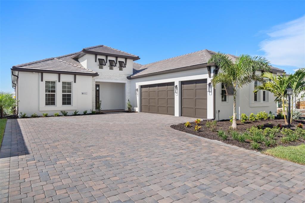 A single-story house with a paved driveway, two-car garage, and white stucco exterior — 832 BLUE SHELL LOOP, SARASOTA, FL