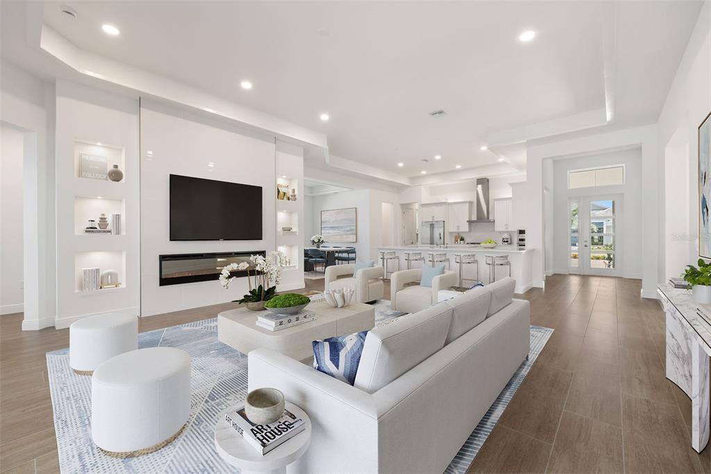 A bright, open-concept living room and kitchen featuring white cabinetry, a fireplace, and tile flooring — 832 BLUE SHELL LOOP, SARASOTA, FL