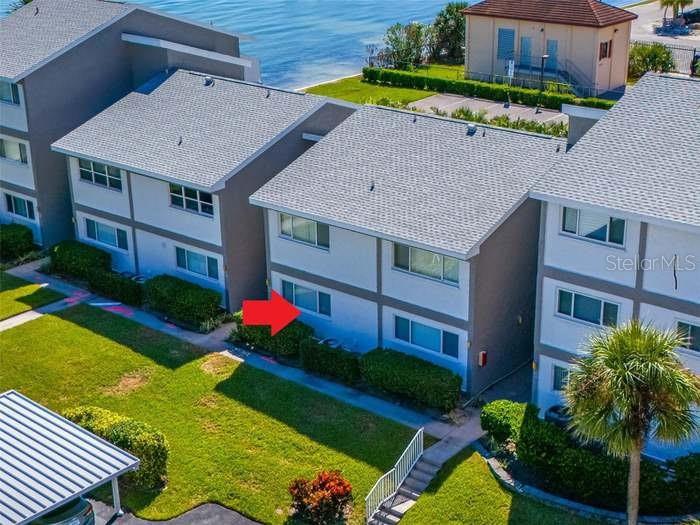 An aerial view shows the exterior of a multi-story residential building with a red arrow — 1351 GULF BOULEVARD UNIT 118, CLEARWATER BEACH, FL