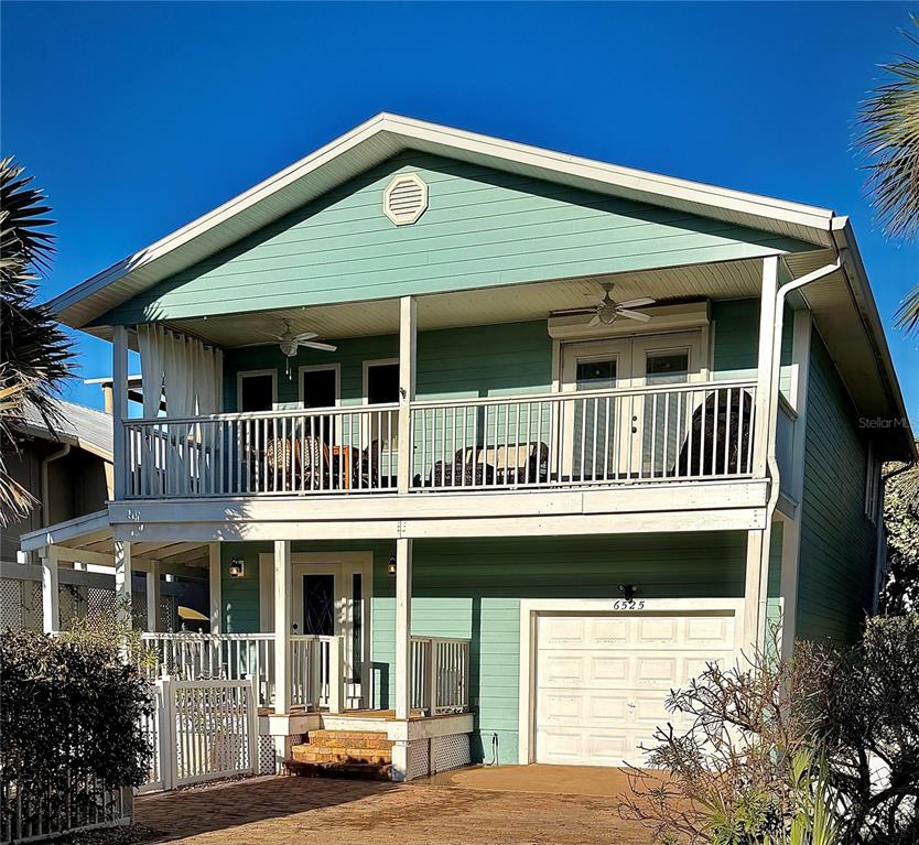 A two-story house with light green siding, a white balcony, and a ground-level garage — 6525 ENGRAM ROAD, NEW SMYRNA BEACH, FL