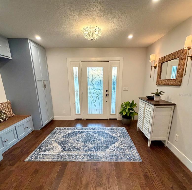 An entryway features a blue rug, a built-in bench, a cabinet, and a glass-paneled door — 6525 ENGRAM ROAD, NEW SMYRNA BEACH, FL