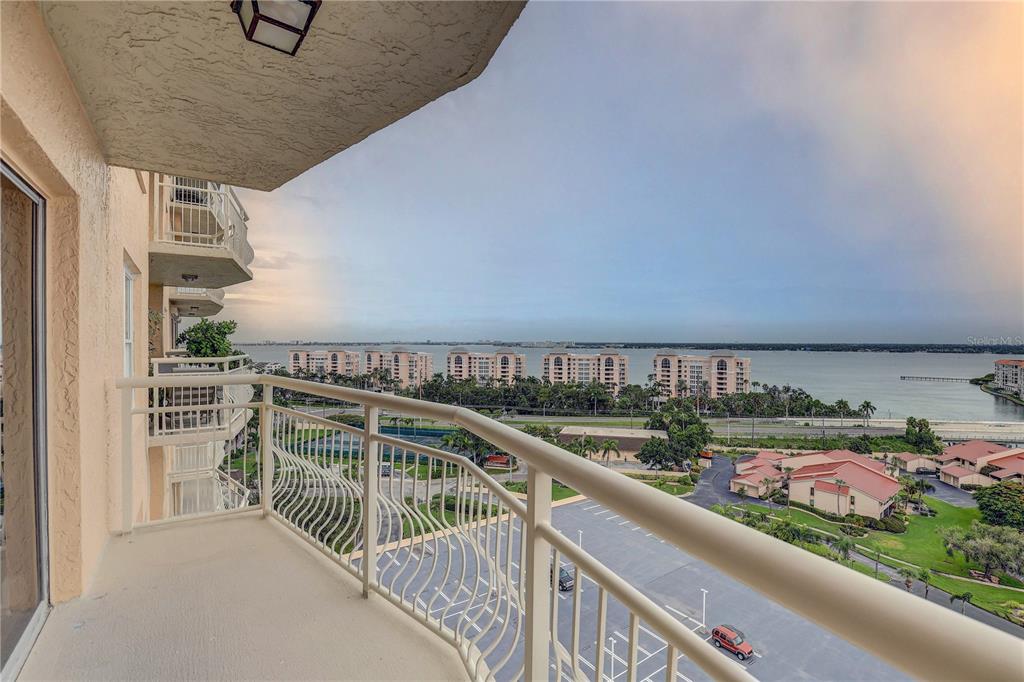A high-angle view from a balcony overlooking a parking lot, green space, and the ocean — 4900 BRITTANY DRIVE S UNIT 1409, ST PETERSBURG, FL