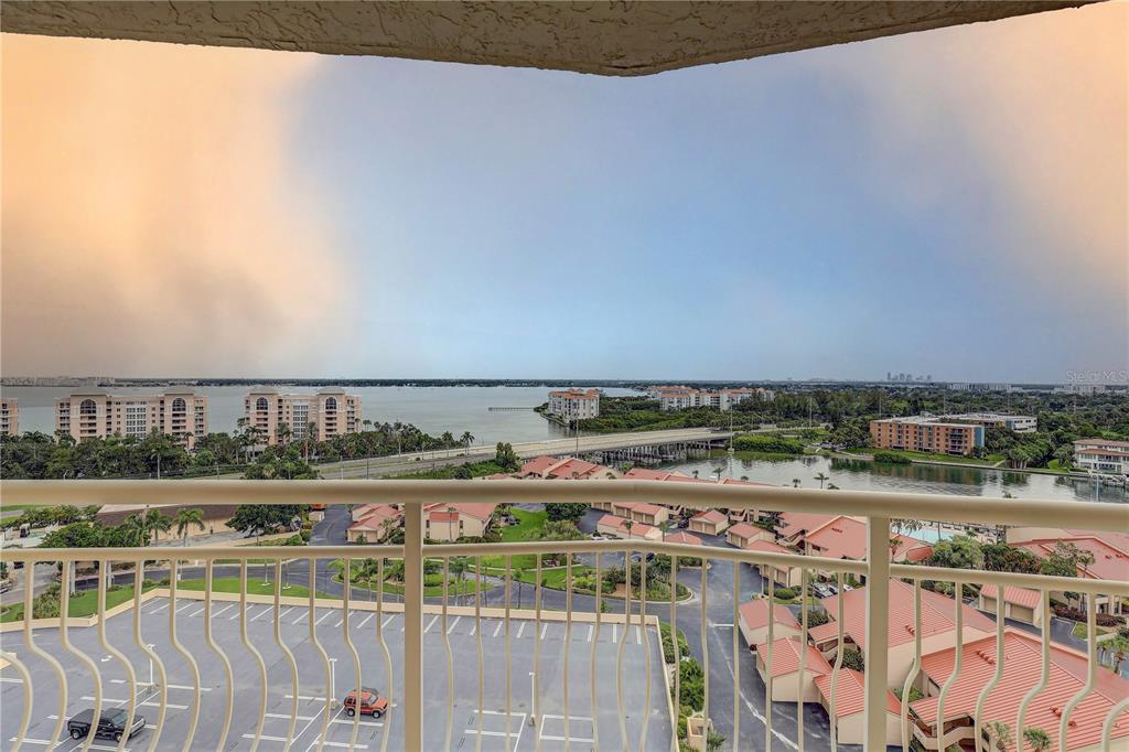 A high-angle view from a balcony overlooking a parking lot, residential buildings, and a bay — 4900 BRITTANY DRIVE S UNIT 1409, ST PETERSBURG, FL