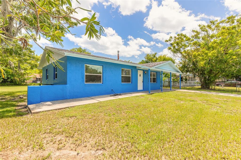 A bright blue single-story house with a covered porch sits on a grassy lot — 901 LOCKHART STREET, DAYTONA BEACH, FL