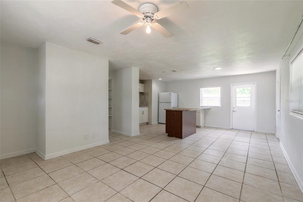 An open-concept kitchen and living area features white walls, light tile flooring, and a ceiling fan — 901 LOCKHART STREET, DAYTONA BEACH, FL