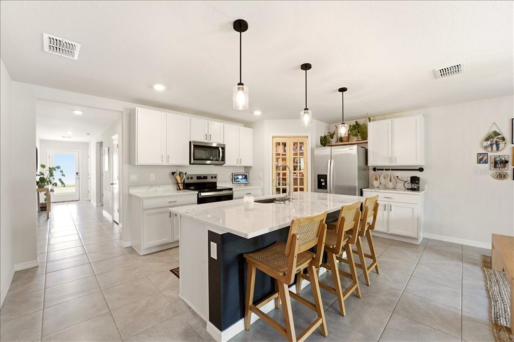 A single-story suburban house with a tan stucco exterior, a two-car garage, and a lawn — 12273 MOUNTAIN ISLAND TRAIL, PARRISH, FL