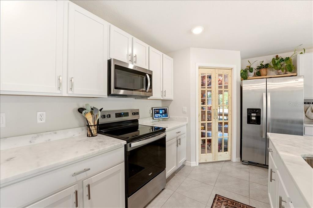 A modern open-concept kitchen with white cabinets, a central island, and an adjacent living area — 12273 MOUNTAIN ISLAND TRAIL, PARRISH, FL