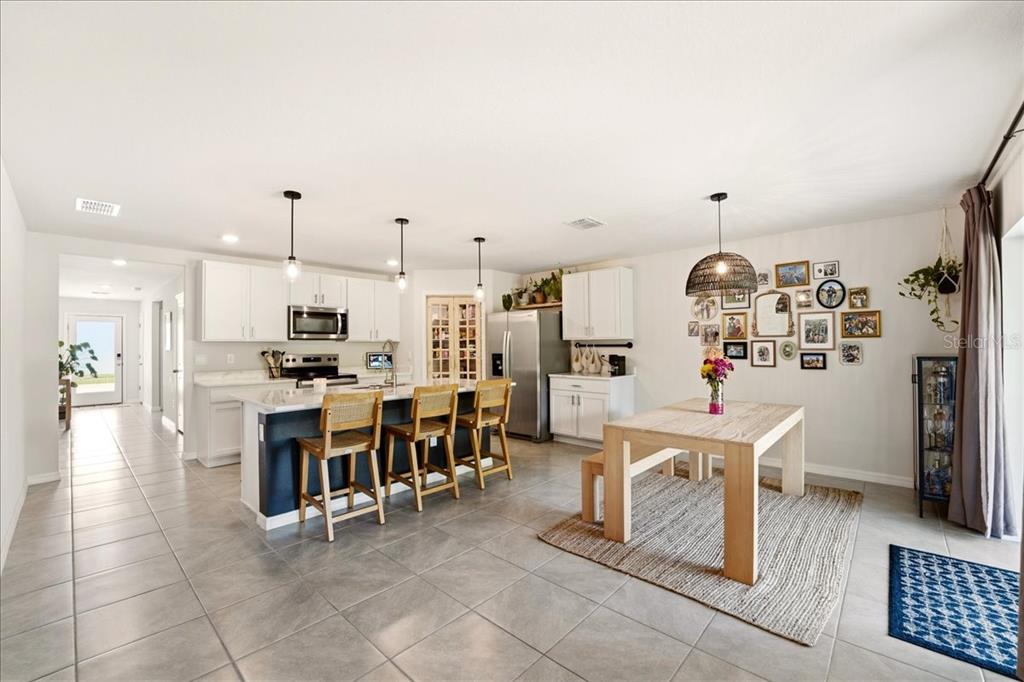 A kitchen features white cabinets, stainless steel appliances, marble-look countertops, and a glass-paneled pantry door — 12273 MOUNTAIN ISLAND TRAIL, PARRISH, FL