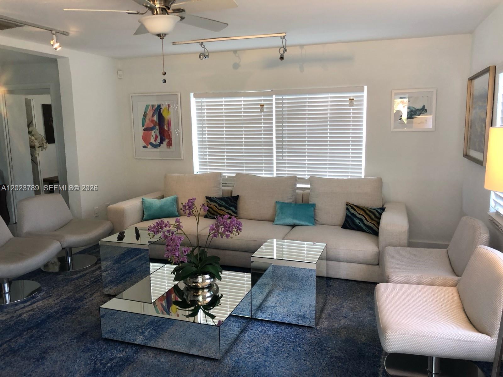 A living room features a beige sofa, mirrored coffee tables, and blue patterned carpeting — 1918 Liberty St # 0, Hollywood FL 33020, HOLLYWOOD, FL