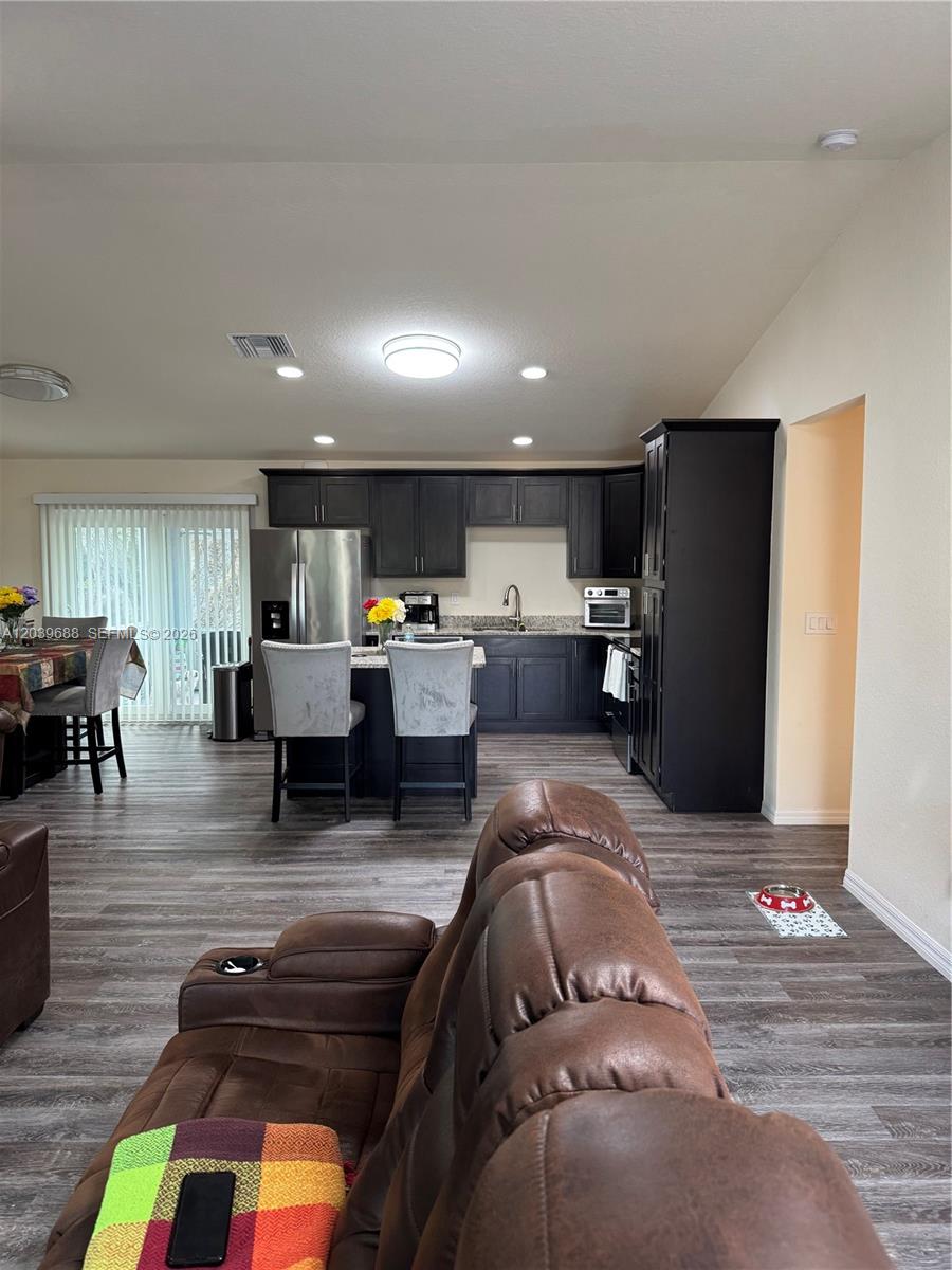 An open-concept kitchen features dark cabinetry, stainless steel appliances, and a central island — 1201 BANJO CT, La Belle FL 33935, LA BELLE, FL