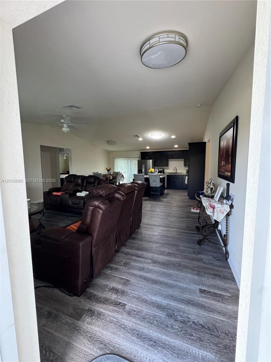 An open-concept living room and kitchen feature dark wood cabinetry and gray wood-look flooring — 1201 BANJO CT, La Belle FL 33935, LA BELLE, FL