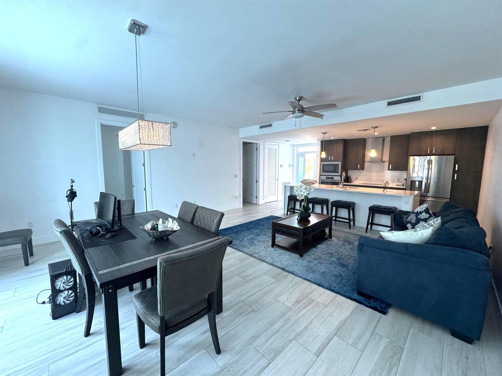 An open-concept living area features a dining table, a blue sofa, and a modern kitchen — 1 S Palmway # 204, FL 33460, FL
