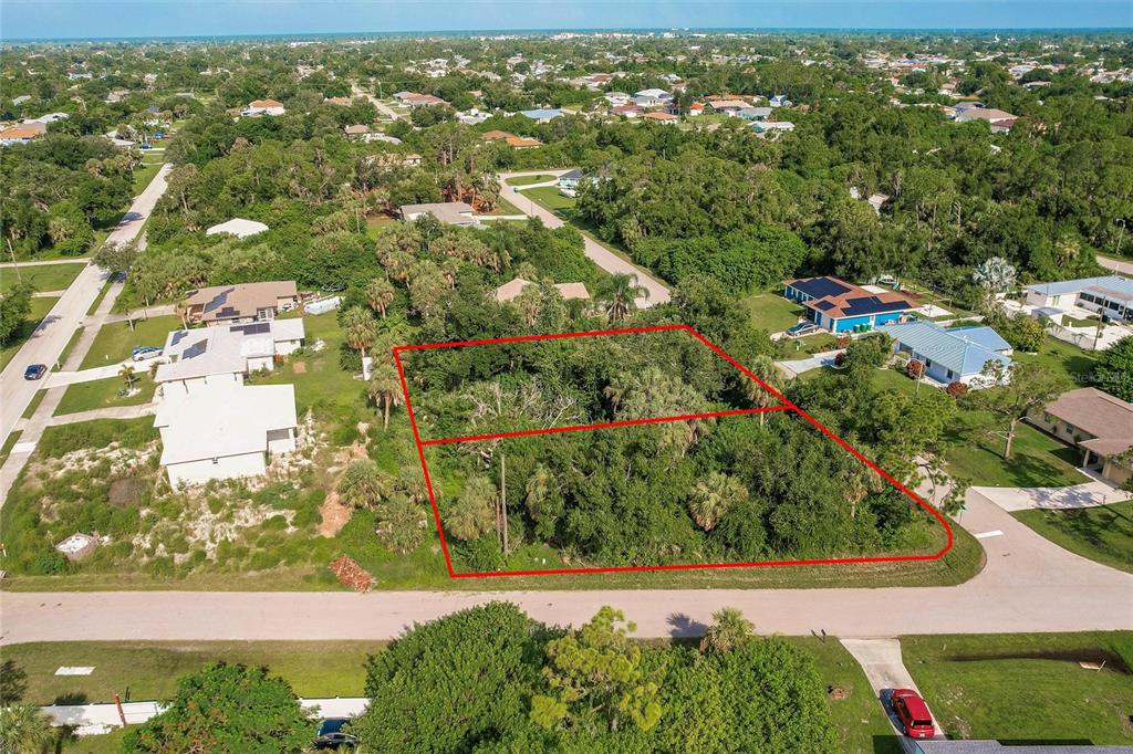 An aerial view shows two adjacent, undeveloped wooded lots outlined in red along a street — 23193 RYE AVENUE, PUNTA GORDA, FL