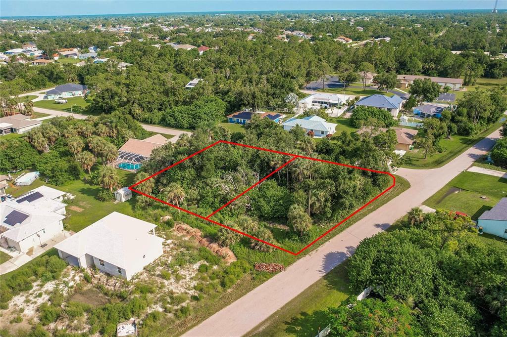 An aerial view shows two adjacent, undeveloped wooded lots outlined in red near a road — 23193 RYE AVENUE, PUNTA GORDA, FL