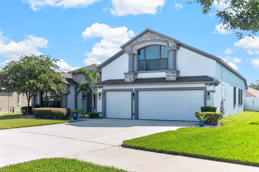 A two-story house features a three-car garage, stucco siding, and a large arched window — 2823 COLEWOOD LANE, DOVER, FL