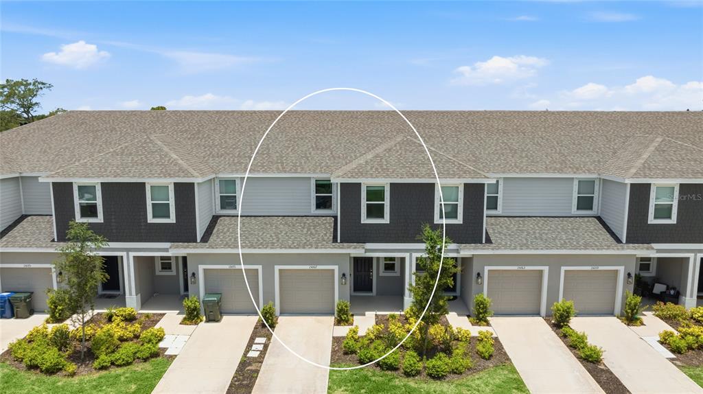 An exterior view of a multi-story townhouse unit with a garage and gray siding — 15067 GINETTI STREET, NOKOMIS, FL