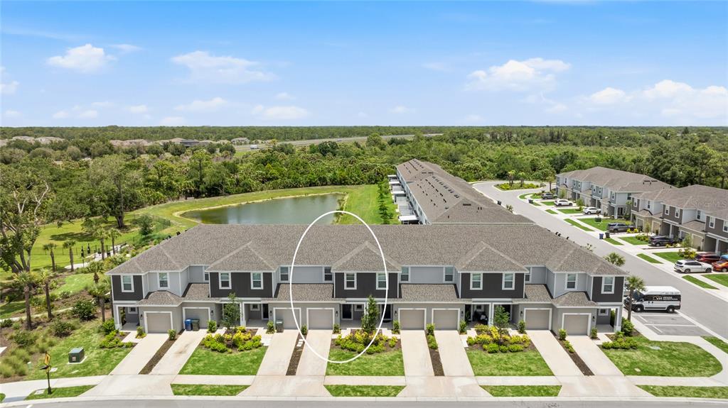 An aerial view shows a row of townhomes with gray siding and a small pond — 15067 GINETTI STREET, NOKOMIS, FL