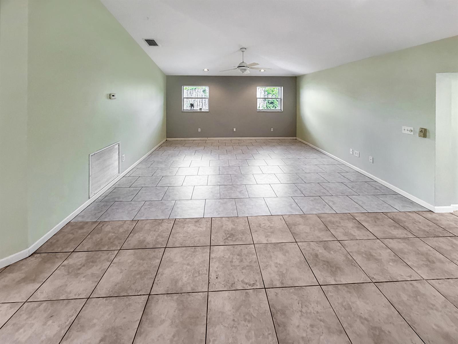 An empty room features light green walls, a grey accent wall, and two-toned tiled flooring — 2361 NE 21st Avenue, Jensen Beach FL 34957, JENSEN BEACH, FL