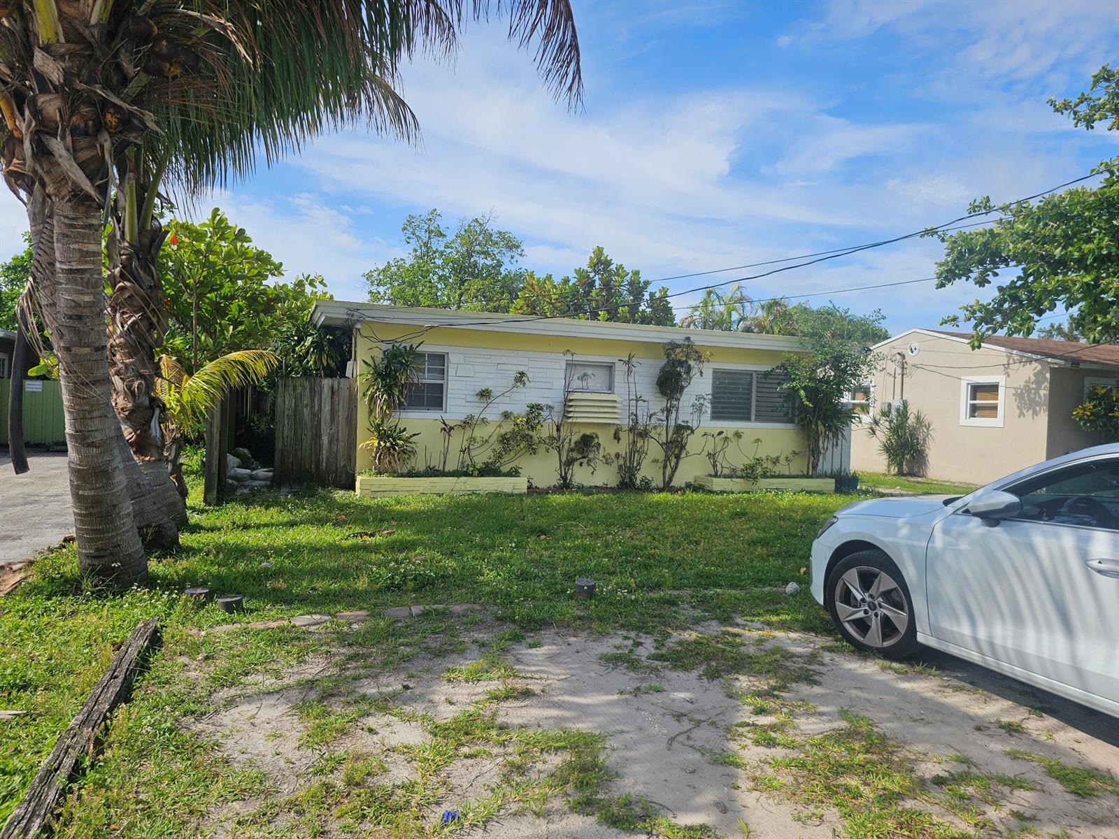 A yellow single-story house with a white stone facade and a palm tree in front — 2512 Arthur Street, Hollywood FL 33020, HOLLYWOOD, FL