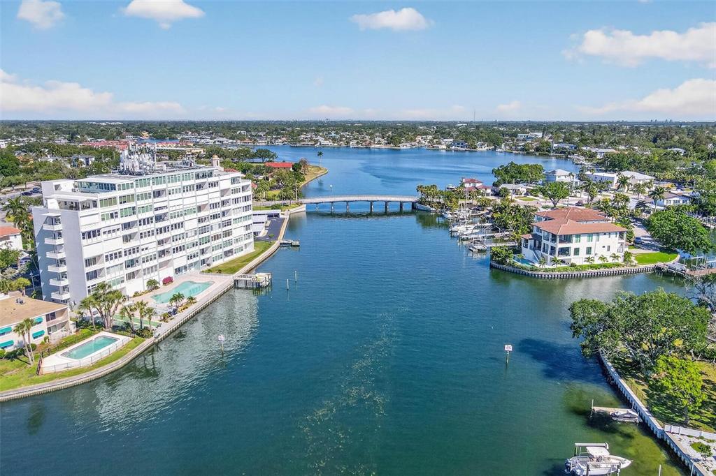 An aerial view shows a large white apartment building beside a canal with a bridge — 1365 SNELL ISLE BOULEVARD NE UNIT 6A, ST PETERSBURG, FL