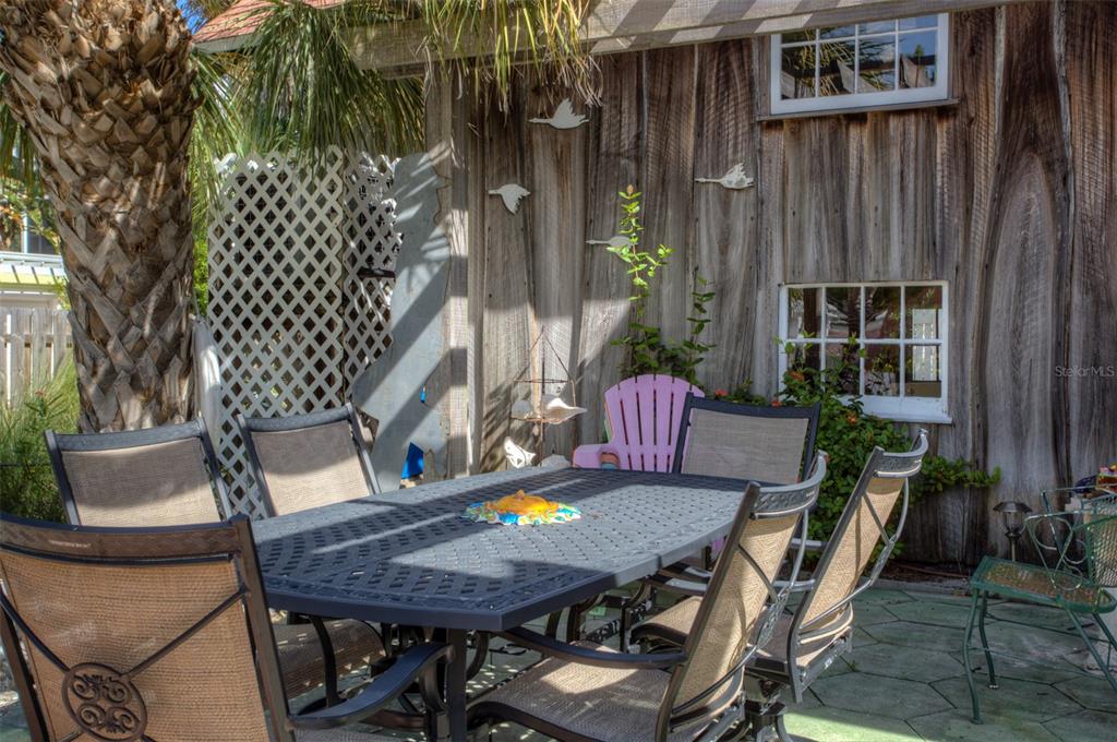 A patio with a metal dining set sits beside a weathered wood-sided building with windows — 3000 PASS A GRILLE WAY, ST PETE BEACH, FL
