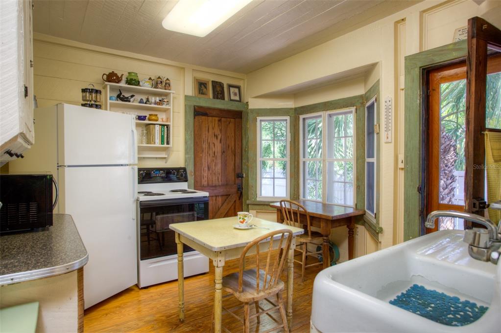 A rustic kitchen features a white refrigerator, a stove, a small table, and a farmhouse sink — 3000 PASS A GRILLE WAY, ST PETE BEACH, FL