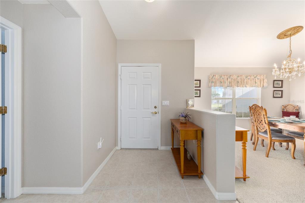 An entryway features tile flooring, a white front door, and a half-wall beside a dining area — 8789 SE 136TH LANE, SUMMERFIELD, FL