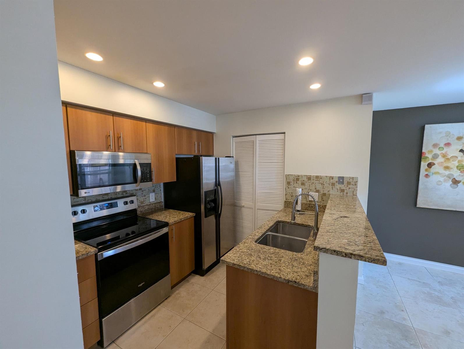 A kitchen features wood cabinets, granite countertops, stainless steel appliances, and a tiled backsplash — 1335 Crystal Way, Delray Beach FL 33444, DELRAY BEACH, FL