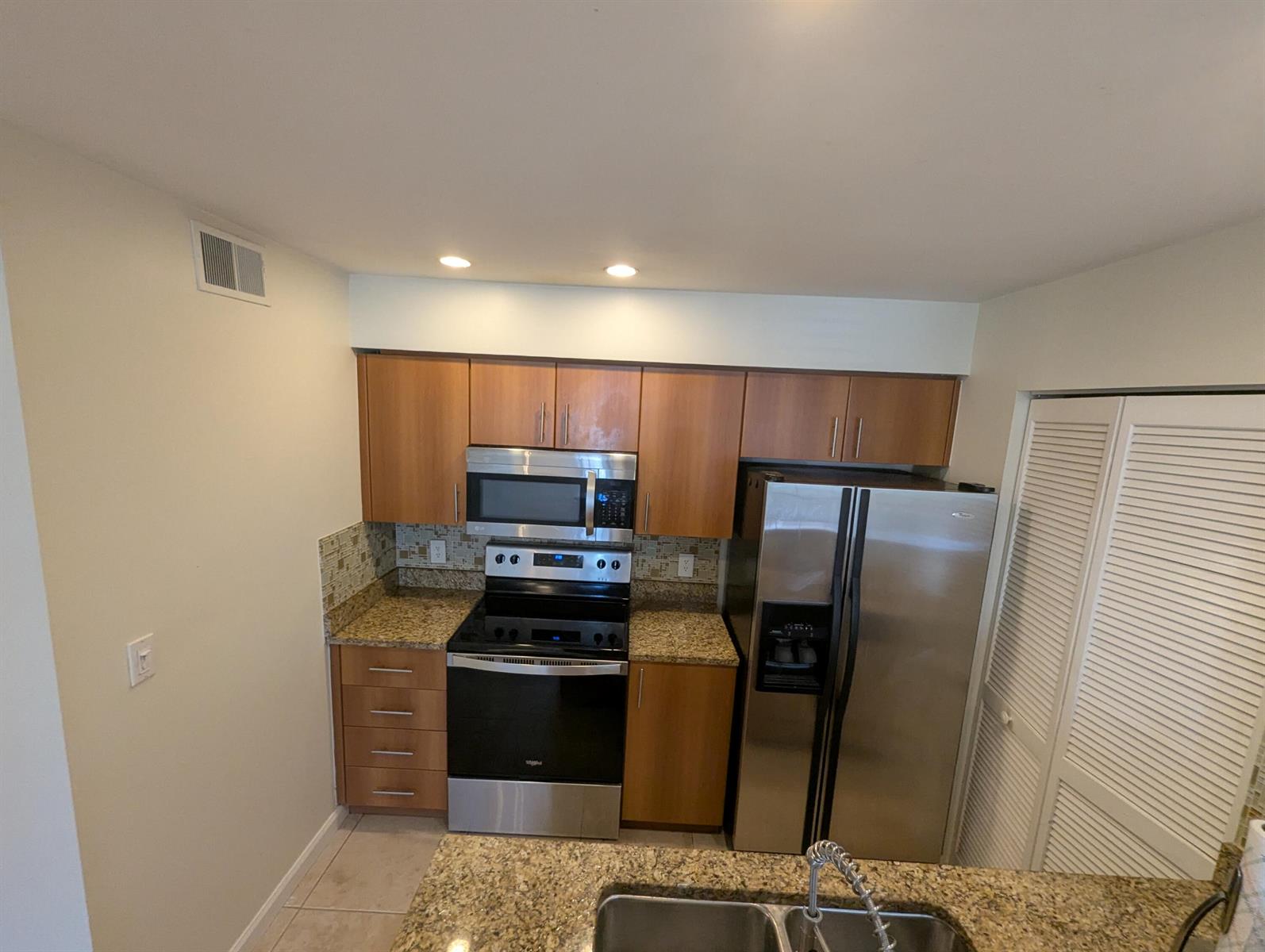 A kitchen features wood cabinets, stainless steel appliances, and granite countertops — 1335 Crystal Way, Delray Beach FL 33444, DELRAY BEACH, FL