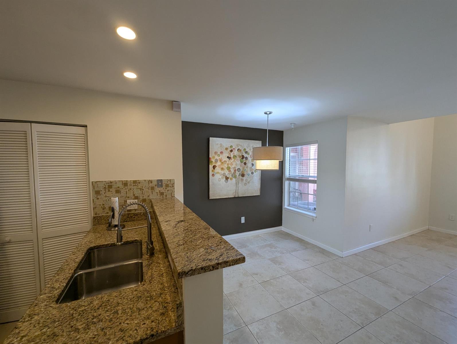 A kitchen with granite countertops and a double sink overlooks an adjacent dining area — 1335 Crystal Way, Delray Beach FL 33444, DELRAY BEACH, FL