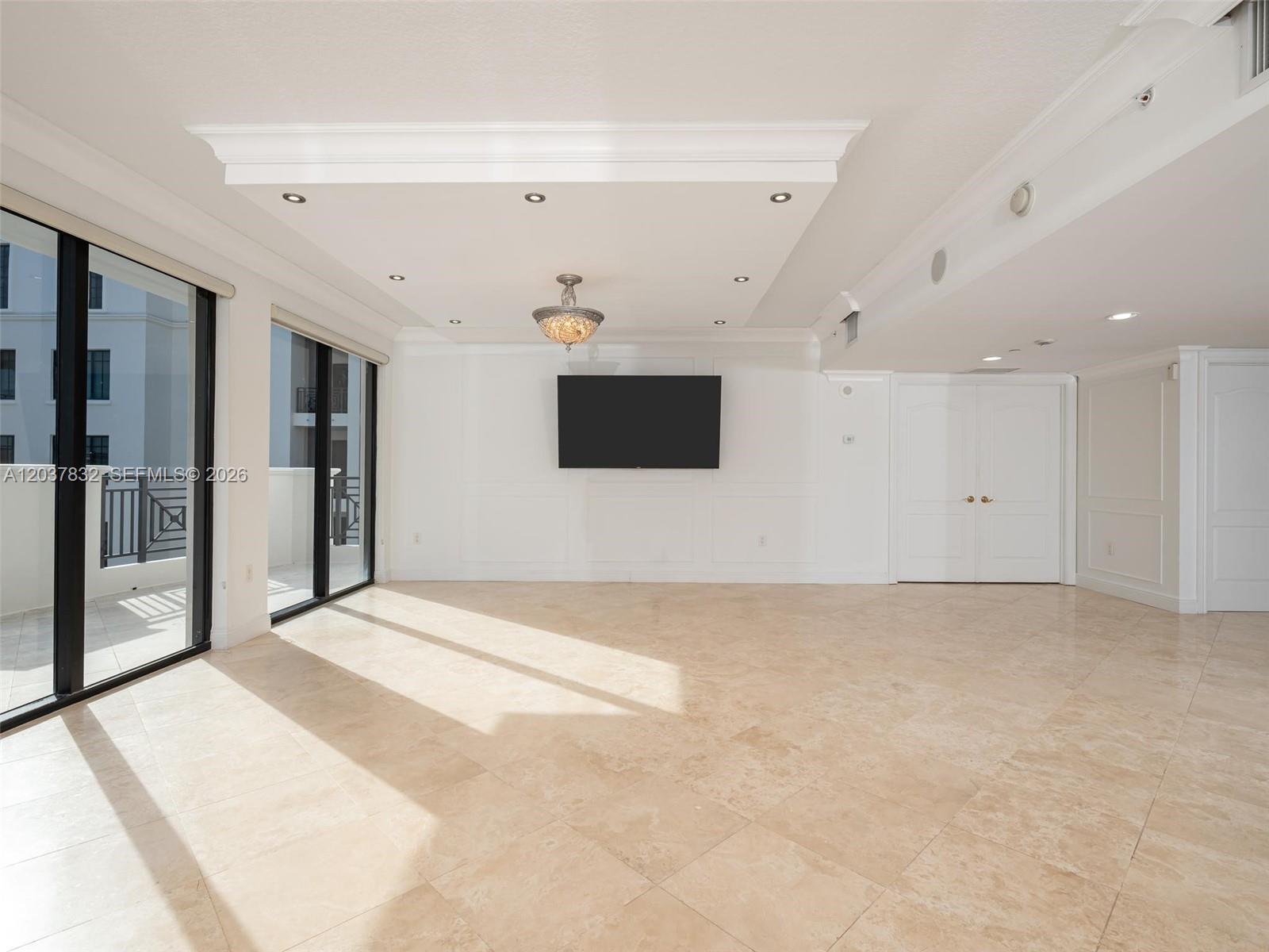 A bright, empty living room features tile flooring, a wall-mounted television, and floor-to-ceiling windows — 200 E Palmetto Park Rd # 700, Boca Raton FL 33432, BOCA RATON, FL