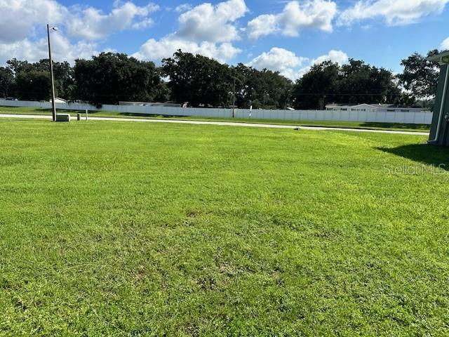 A flat, grassy vacant lot is bordered by a white fence and mature trees — 118 LAYNEWADE ROAD, POLK CITY, FL