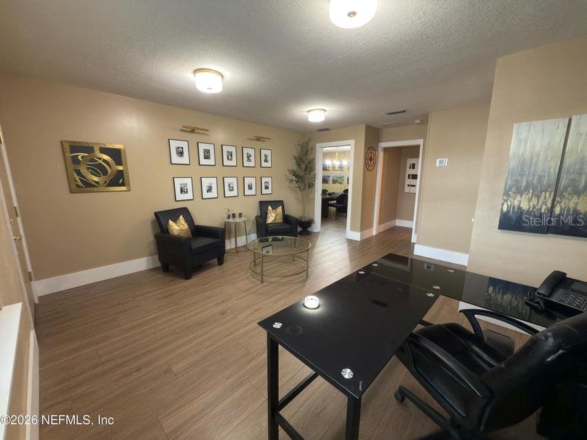 A home office features a black glass desk, two armchairs, and a gallery wall — 160 SW NIGHTINGALE STREET, KEYSTONE HEIGHTS, FL